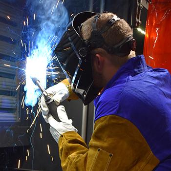 Male student welding with sparks spraying up and down